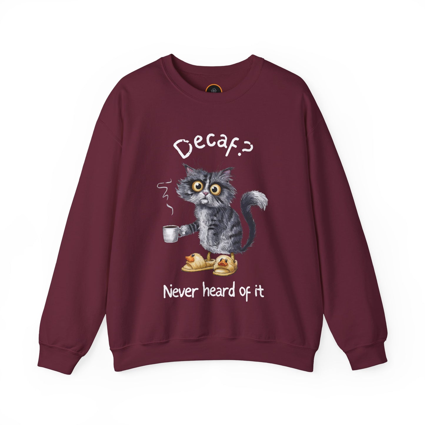 A sweatshirt featuring an exhausted-looking cat wearing yellow slippers with duck faces on them. The cat is holding a steaming mug of coffee. The text on the sweatshirt reads "Decaf? Never Heard of It."