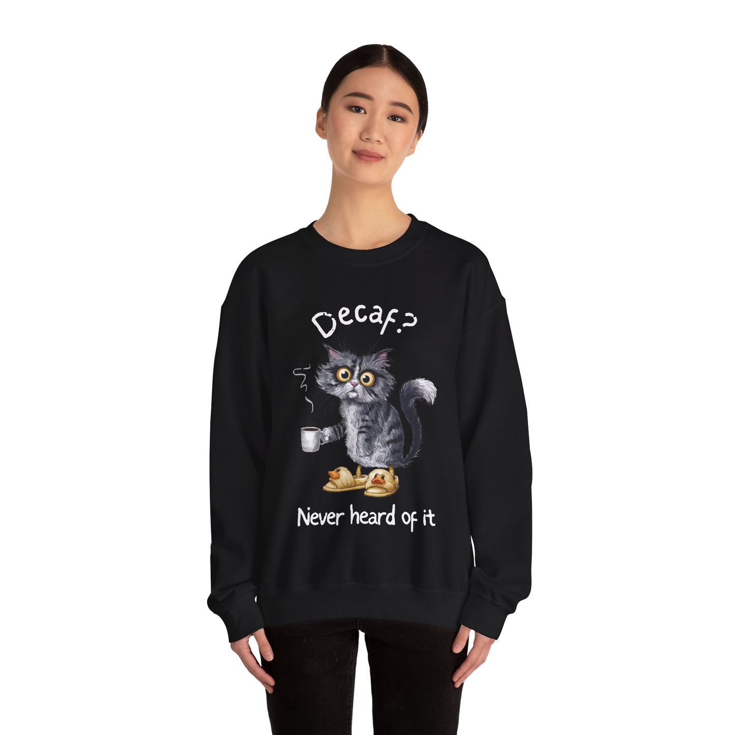 A sweatshirt featuring an exhausted-looking cat wearing yellow slippers with duck faces on them. The cat is holding a steaming mug of coffee. The text on the sweatshirt reads "Decaf? Never Heard of It."