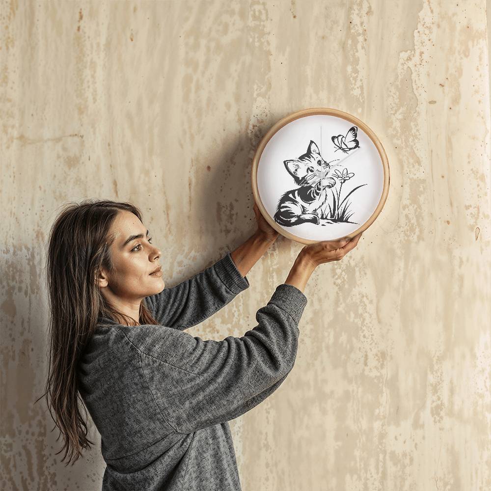 A clock featuring a line art design of a playful encounter between a curious kitten and a gentle butterfly