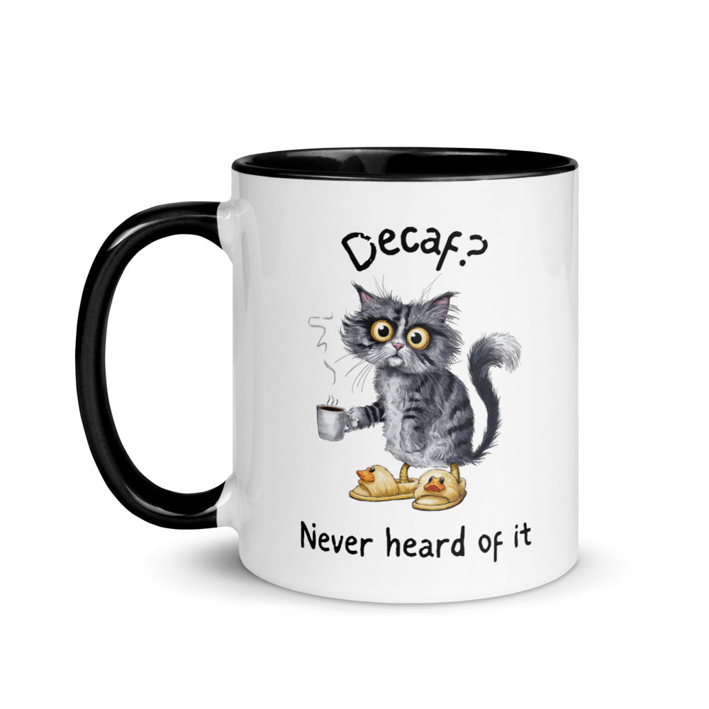 A white and black mug featuring an exhausted looking cat wearing yellow slippers with duck faces on them. The cat is holding a steaming mug of coffee. The text on the mug reads "Decaf? Never Heard of It."