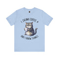 A crew neck t-shirt with the text 'I DRINK COFFEE AND I KNOW THINGS' and an illustration of grumpy a cat holding a coffee cup.
