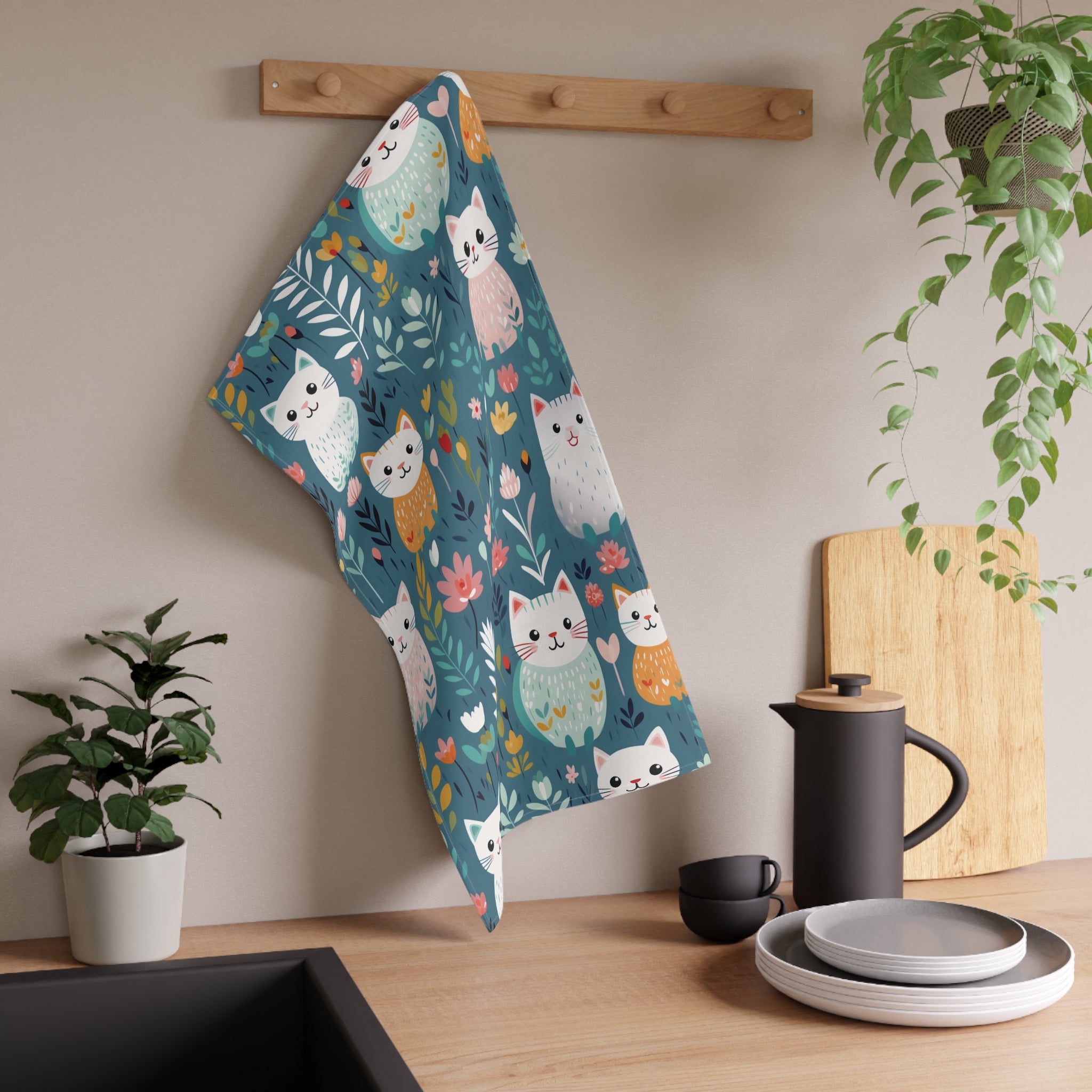 Image of the teal colored Flower Kitty tea towel with a graphic of smiling cats surrounded by flowers.
