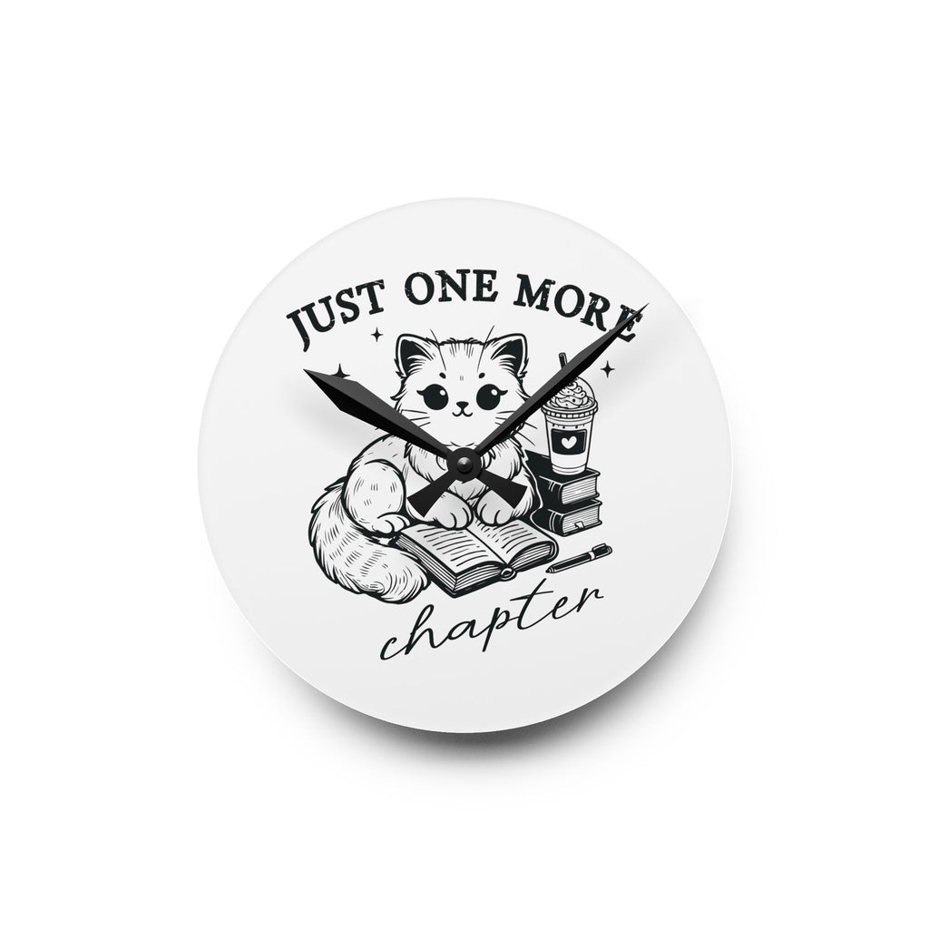 Line art graphic on the "Just One More Chapter" Acrylic Wall Clock depicting a cat reading an open book beside a book stack topped with a beverage. The words "just one more" are above, and "chapter" in script is below.