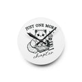 Line art graphic on the "Just One More Chapter" Acrylic Wall Clock depicting a cat reading an open book beside a book stack topped with a beverage. The words "just one more" are above, and "chapter" in script is below.