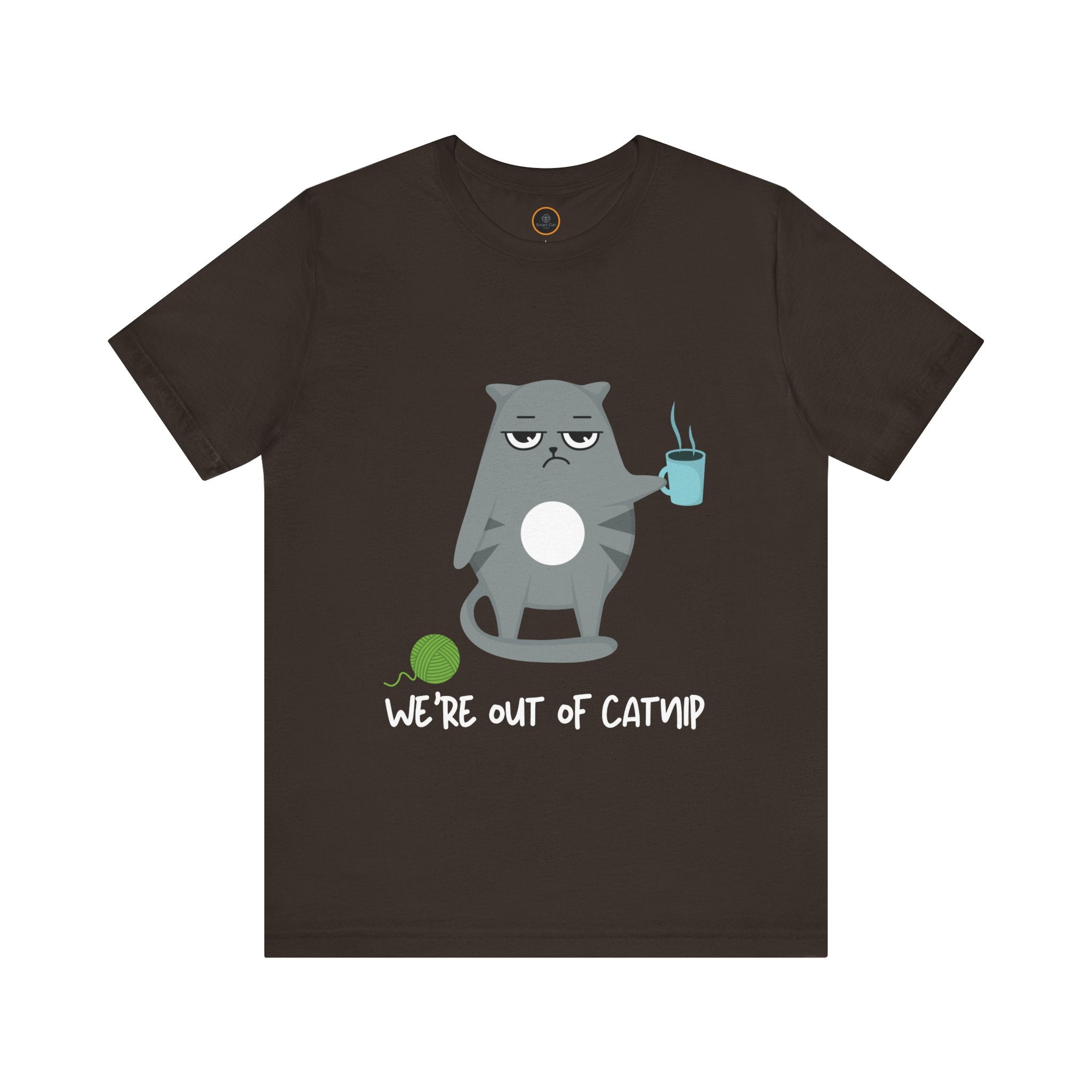 Crewneck t-shirt featuring a cartoon gray and white cat smugly holds a steaming cup of coffee. A green ball of yarn sits on the floor nearby. Below the image, the text reads "We're Out Of Catnip".