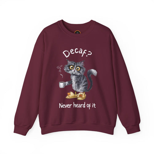 A sweatshirt featuring an exhausted-looking cat wearing yellow slippers with duck faces on them. The cat is holding a steaming mug of coffee. The text on the sweatshirt reads "Decaf? Never Heard of It."