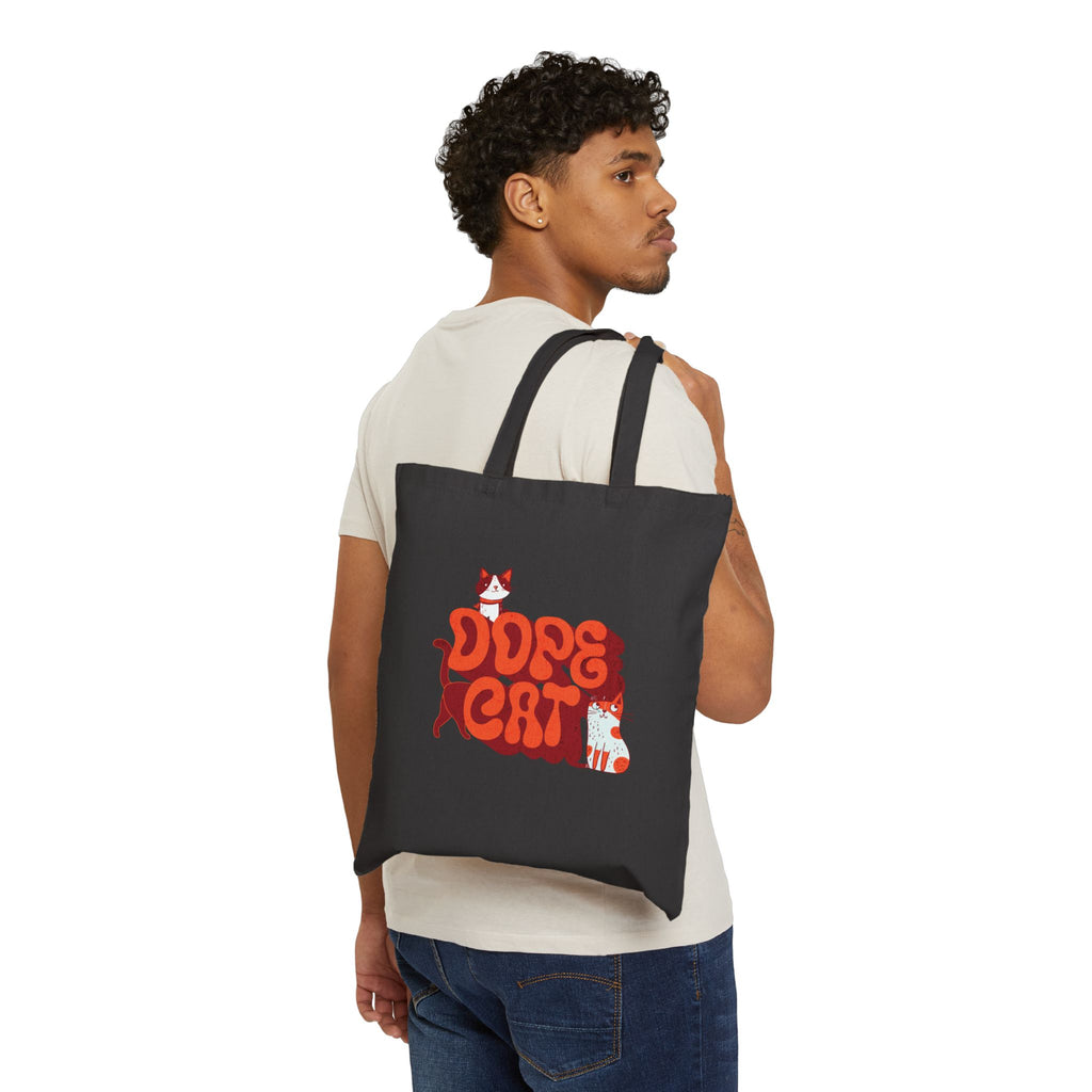 Man holding a black tote bag with red and white 'Dope Cat' text and cat graphics