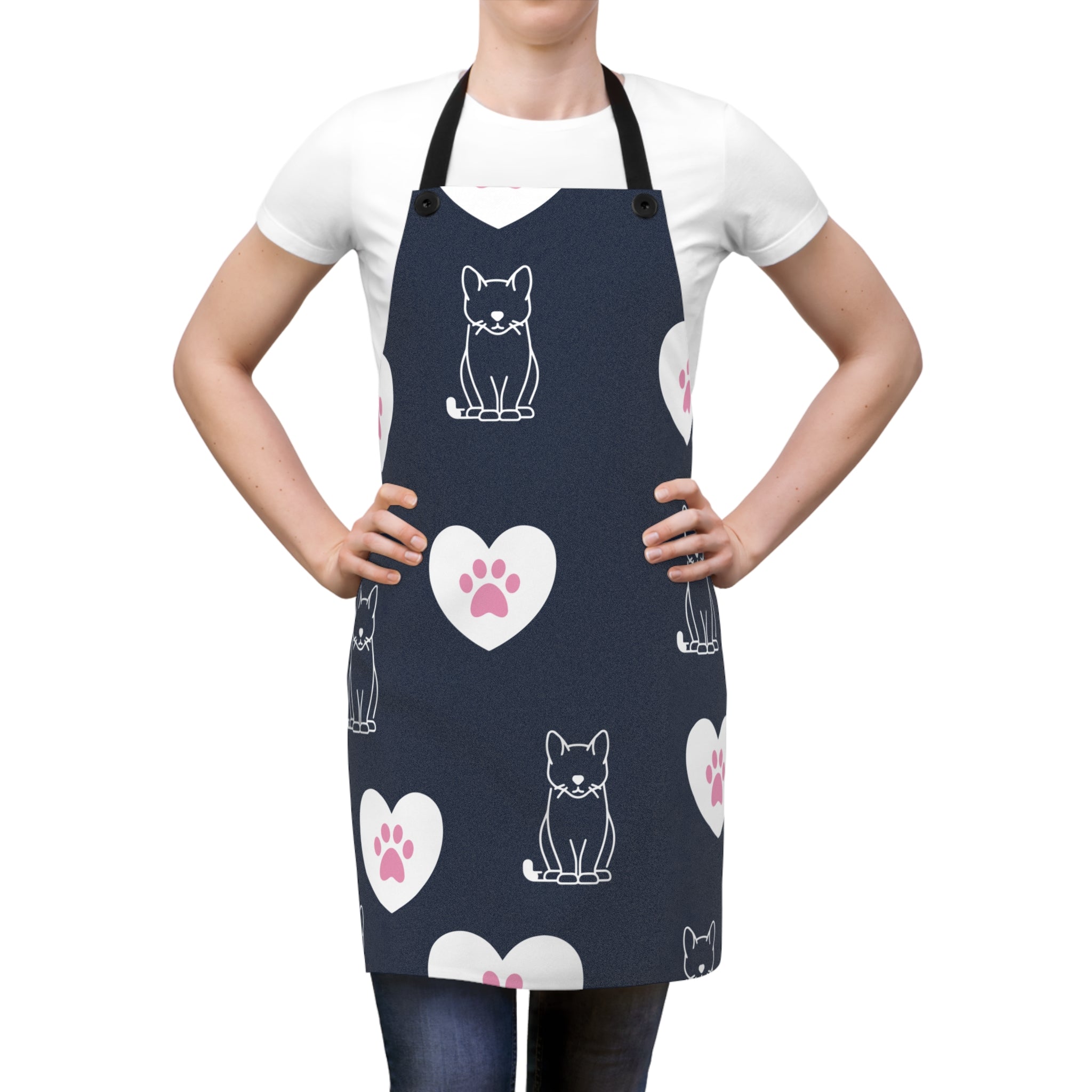 mage of a woman wearing the blue Pink Paws and Hearts apron with a graphic of pink cat paws in white hearts surrounded by line art house cats.