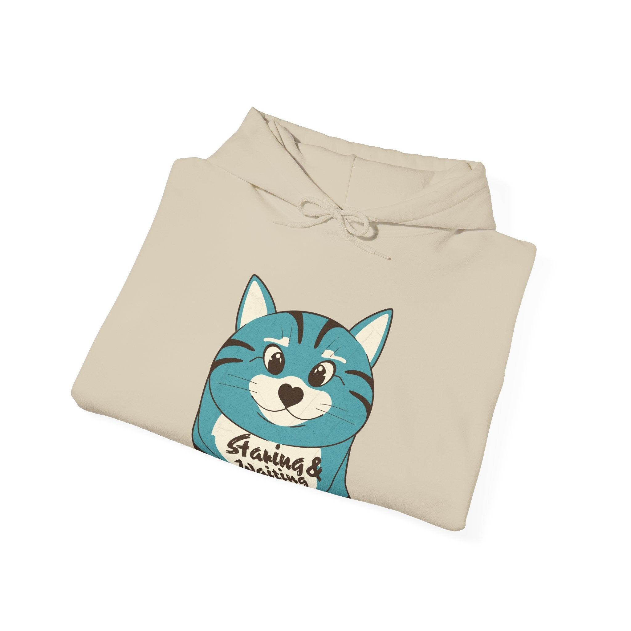 A folded beige "Staring and Waiting" Hoodie: Features a cartoon graphic of a wide-eyed cat on the front, with the text "staring and waiting" written across its belly.
