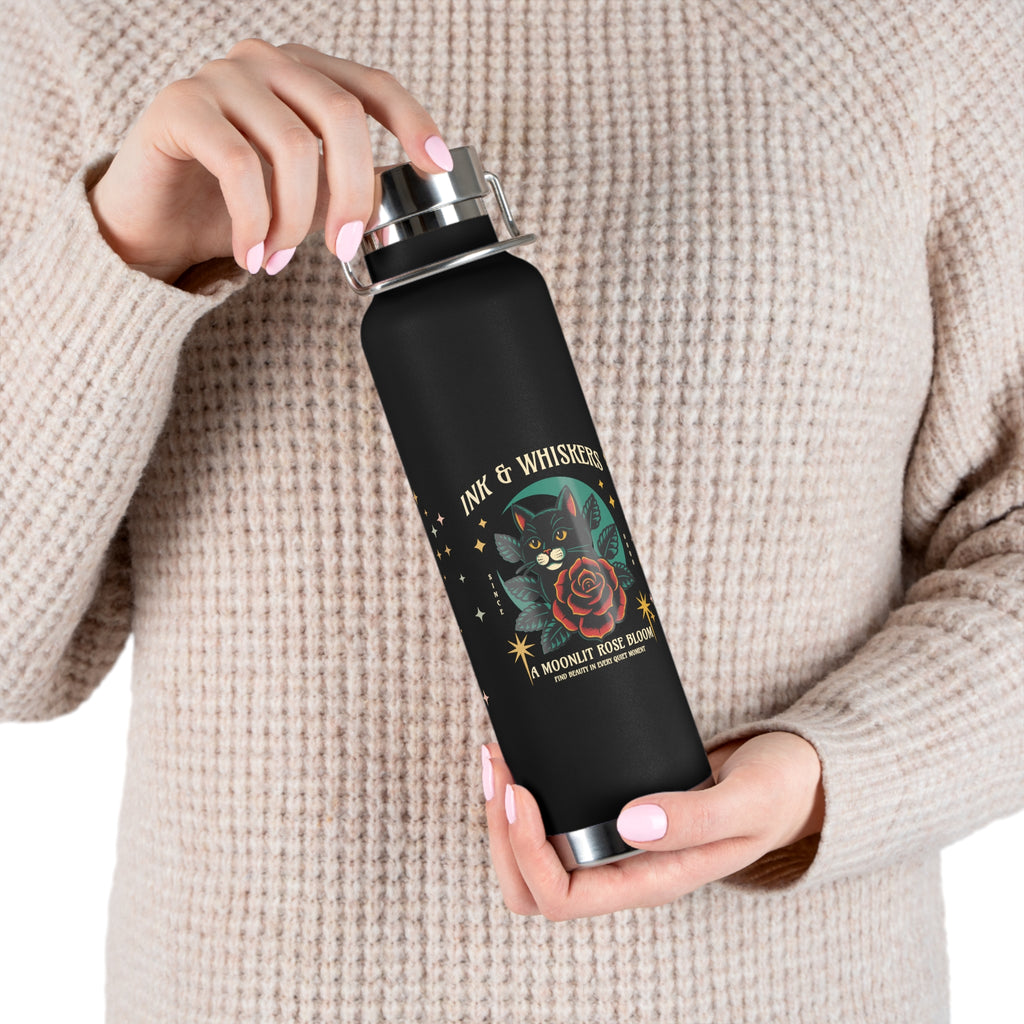 Model holding a black water bottle with cat and rose design, featuring the text 'Ink & Whiskers'.