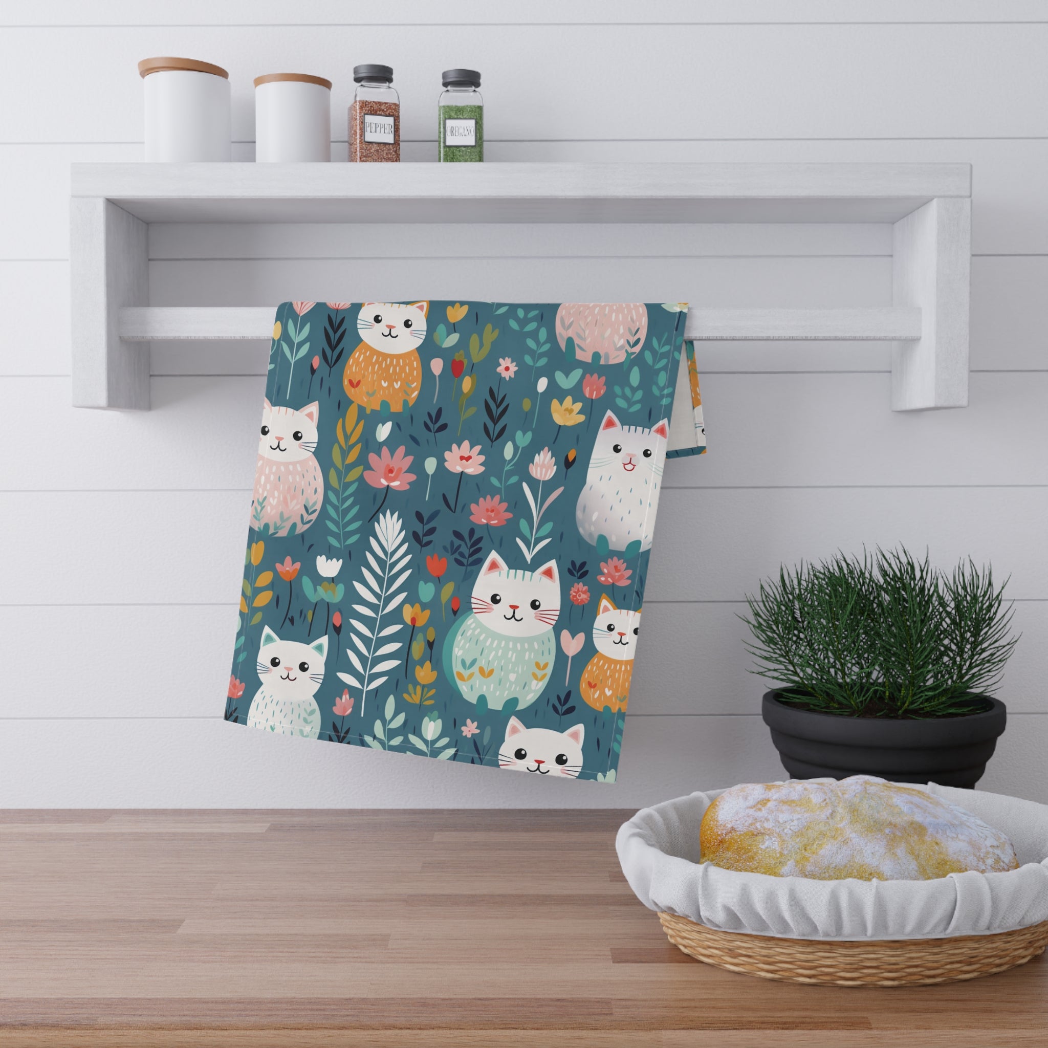 Image of the teal colored Flower Kitty tea towel with a graphic of smiling cats surrounded by flowers. 