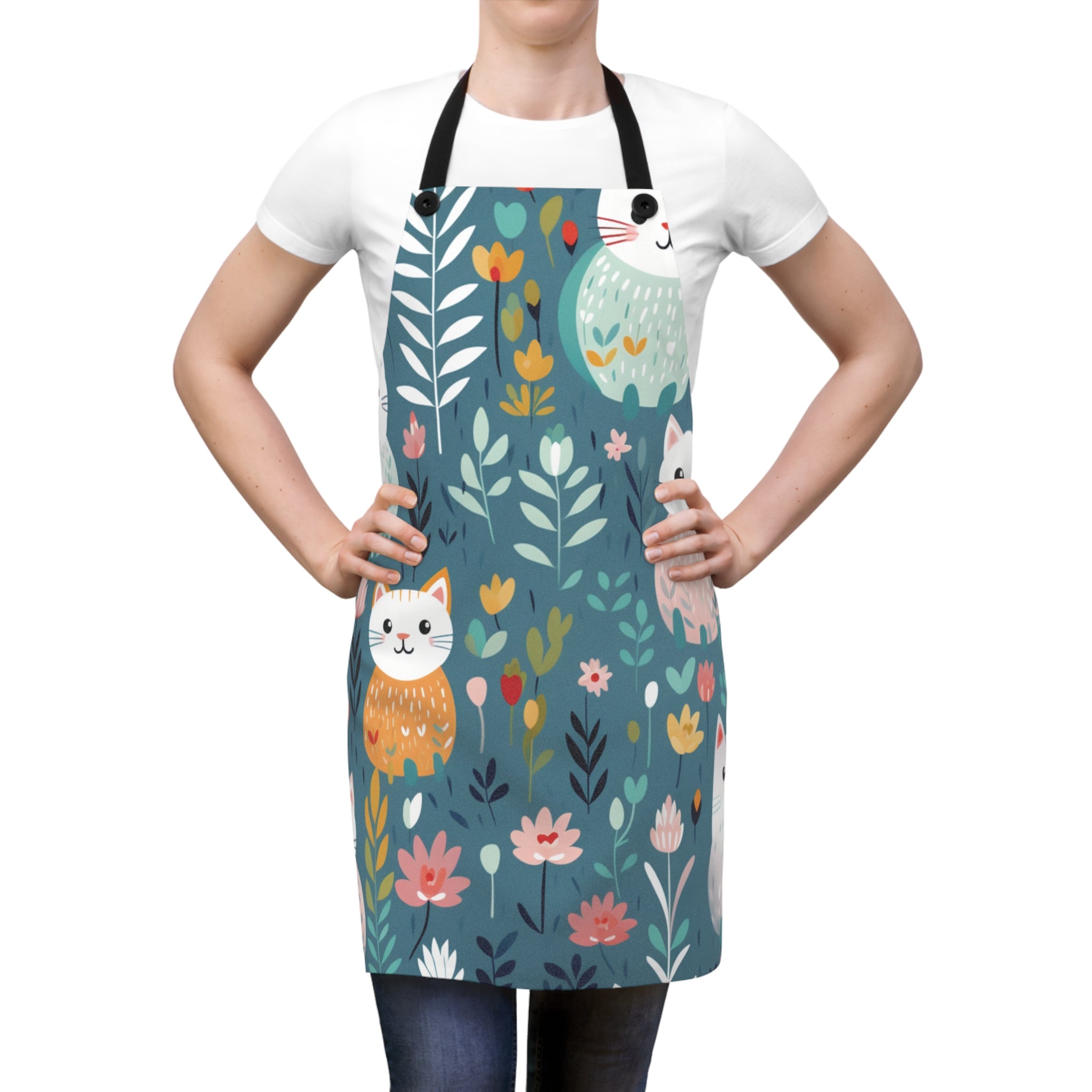 Image of a woman wearing a teal Flower Kitty apron with a graphic of smiling cats surrounded by flowers.