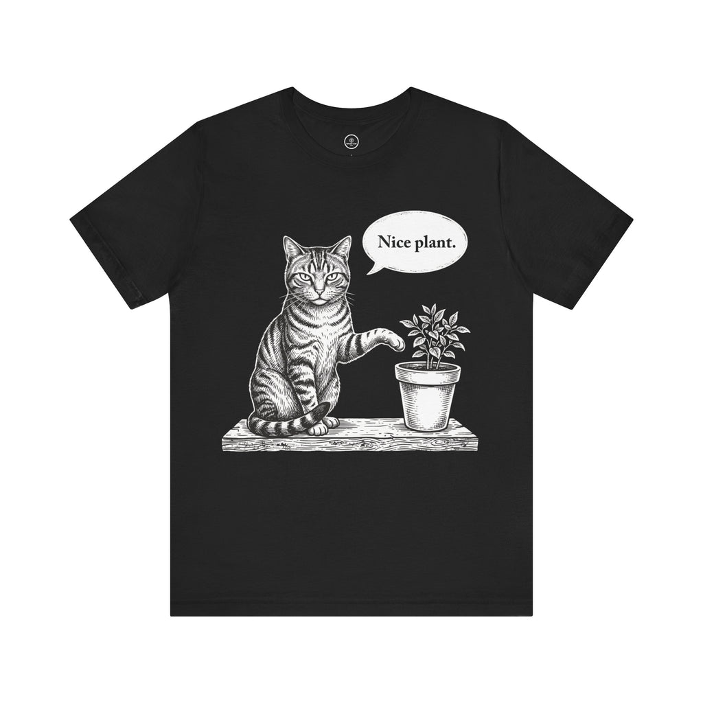 A black short-sleeve crewneck t-shirt featuring a black and white sketch of a cat sitting next to a potted plant with a speech bubble that says 'Nice plant.' on a plain white background.