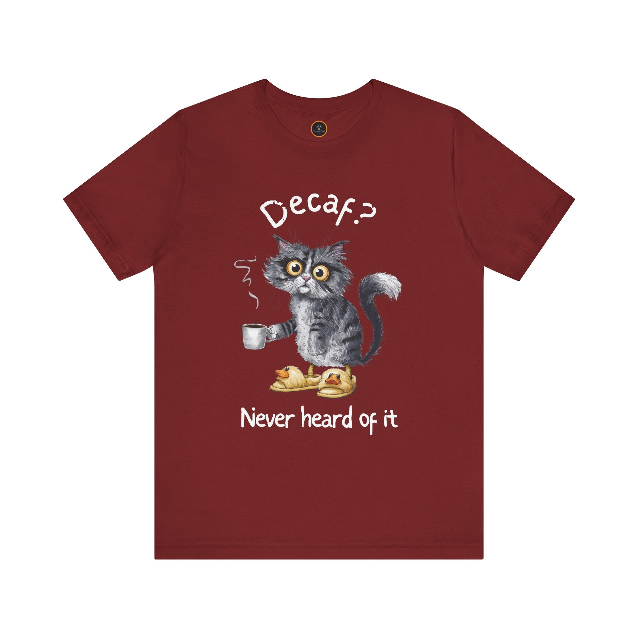 A red crew neck t-shirt featuring an exhausted-looking cat wearing yellow slippers with duck faces on them. The cat is holding a steaming mug of coffee. The text on the sweatshirt reads "Decaf? Never Heard of It."