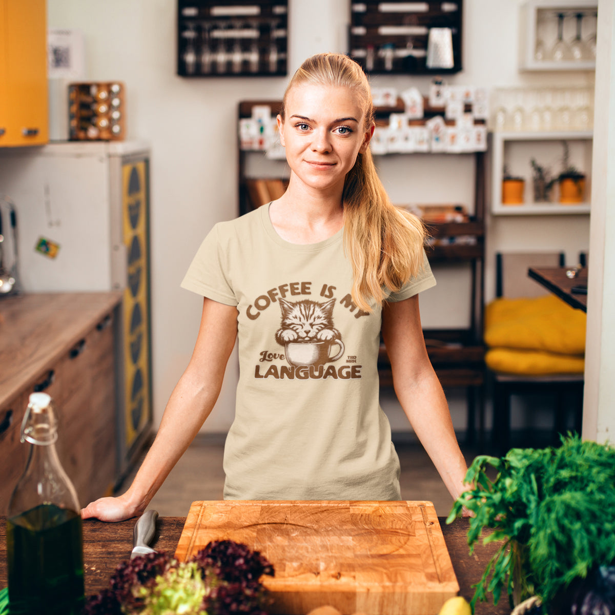 Model wearing a beige crew neck t-shirt with the text 'COFFEE IS MY LOVE LANGUAGE' and a graphic of a cat.