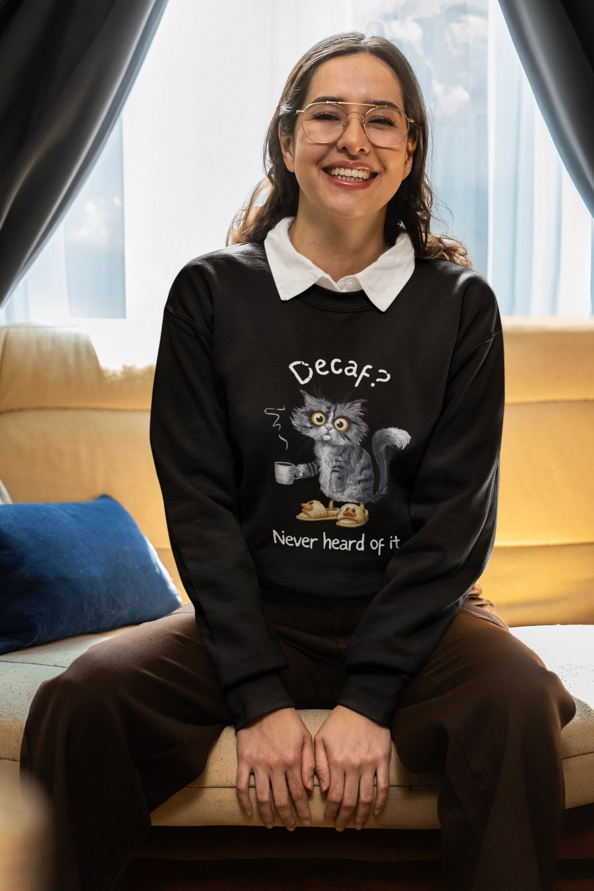 Model wearing black crewneck with gray cat in duck slippers holding coffee, “Decaf? Never heard of it"