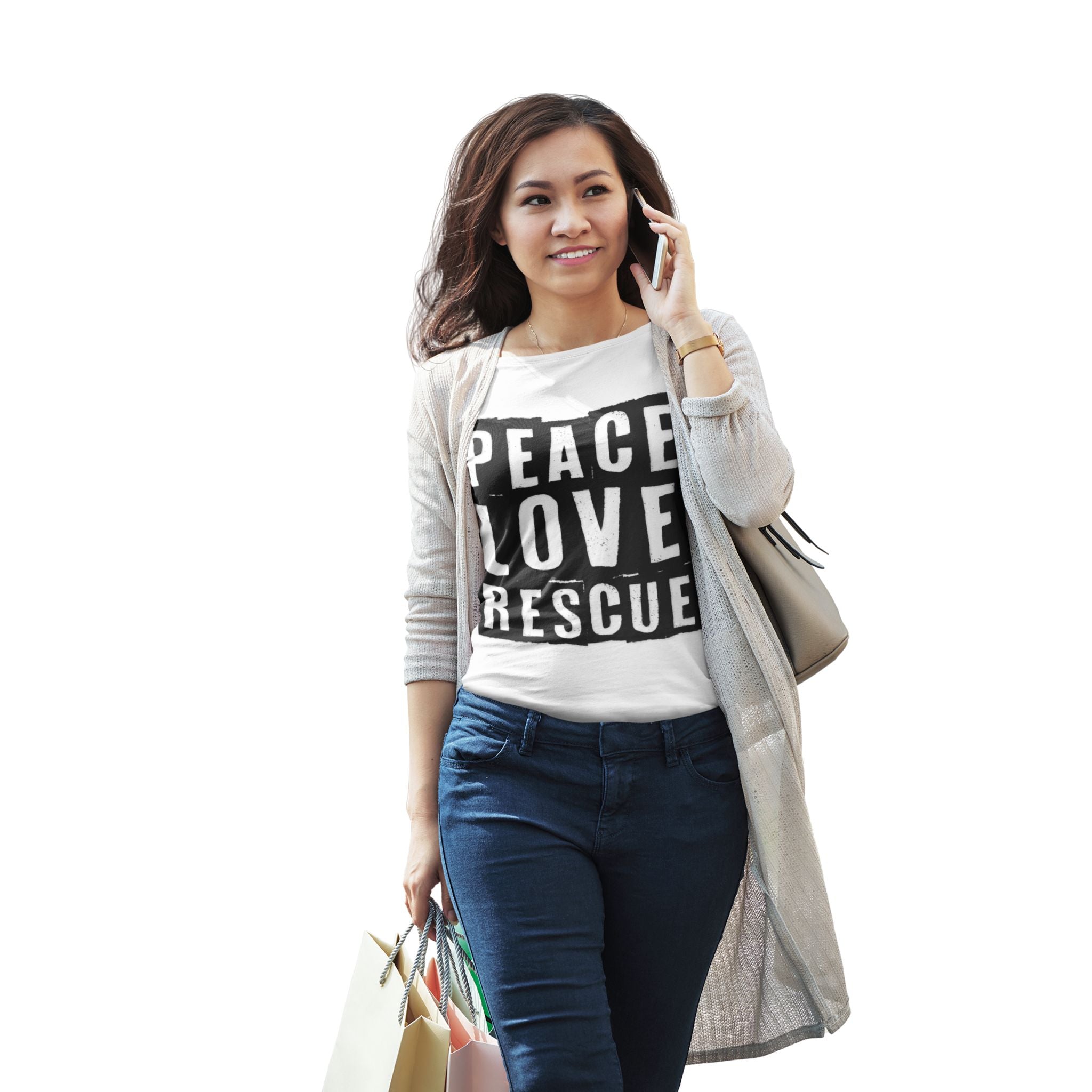 A woman wearing a white crew neck t-shirt with the text 'PEACE LOVE RESCUE' on it, paired with blue jeans and a light beige cardigan. She is carrying shopping bags and smiling while on a cell phone.