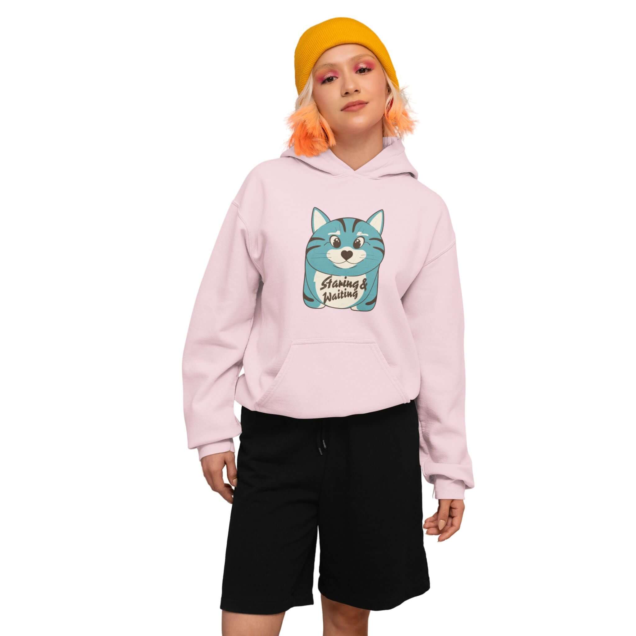 Model wearing the pink "Staring and Waiting" Hoodie: Featuring a cartoon graphic of a wide-eyed cat on the front, with the text "staring and waiting" written across its belly.