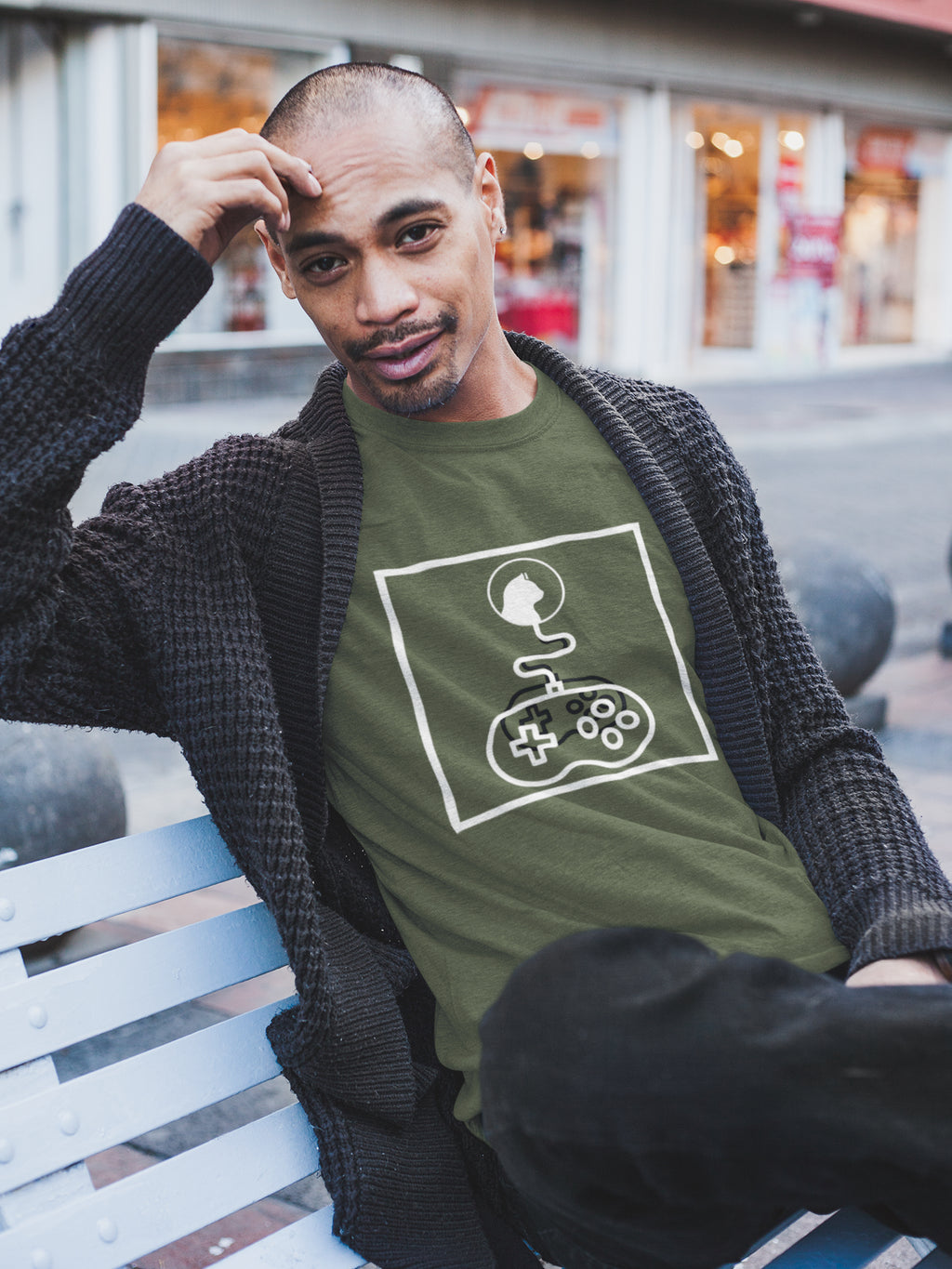 Model wearing a green "System Link Cat" t-shirt: Features a white abstract graphic composed entirely of line art shapes within a box, depicting a cat's head connected by a wire to a video game controller.