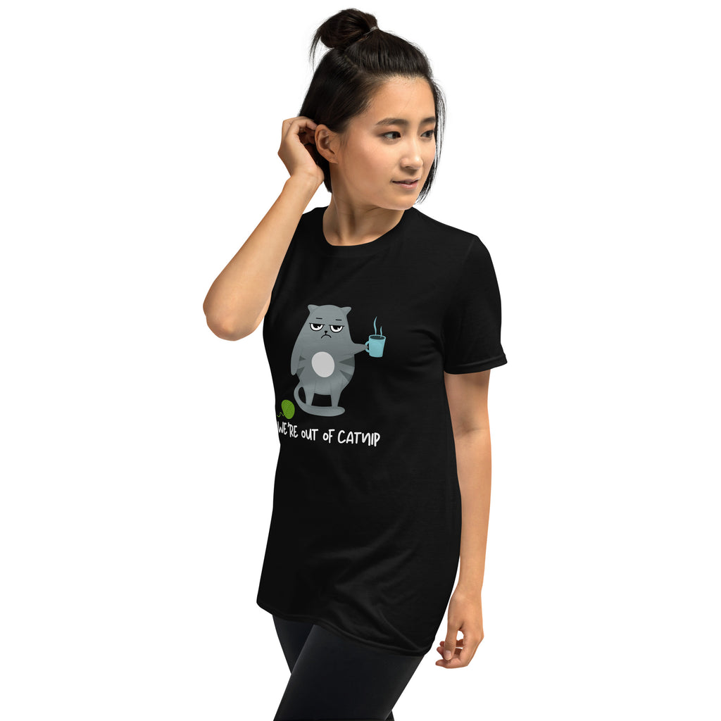 Crewneck t-shirt featuring a cartoon gray and white cat smugly holds a steaming cup of coffee. A green ball of yarn sits on the floor nearby. Below the image, the text reads "We're Out Of Catnip".
