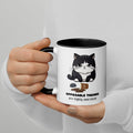 White and black ceramic mug with a graphic of a frustrated cartoon cat standing over spilled coffee. Text below the cat reads "Opposable Thumbs Are Highly Overrated".