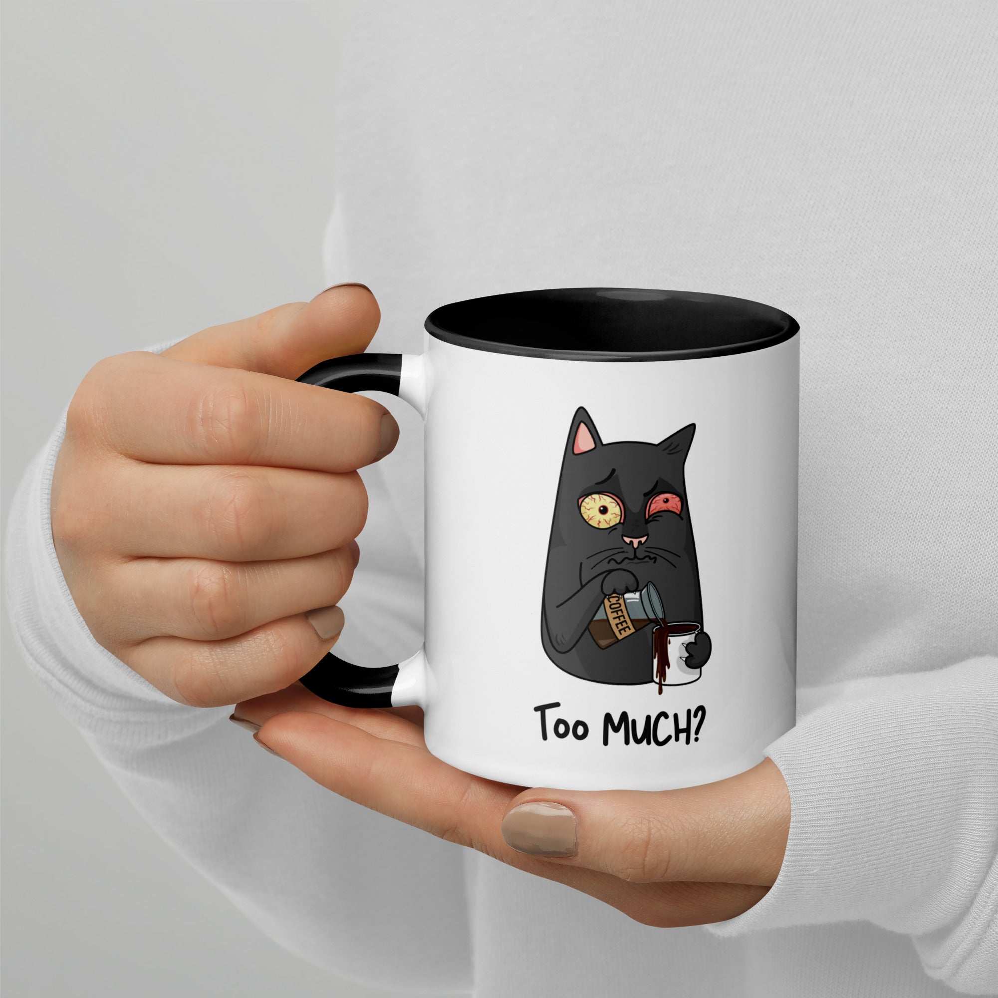 White "Too Much" Mug (showing interior and handle): Graphic of a wide-eyed/red-eyed gray cat pouring overflowing coffee into a cup, with coffee spilling down the side.