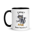 A white and black mug featuring an exhausted looking cat wearing yellow slippers with duck faces on them. The cat is holding a steaming mug of coffee. The text on the mug reads "Decaf? Never Heard of It."