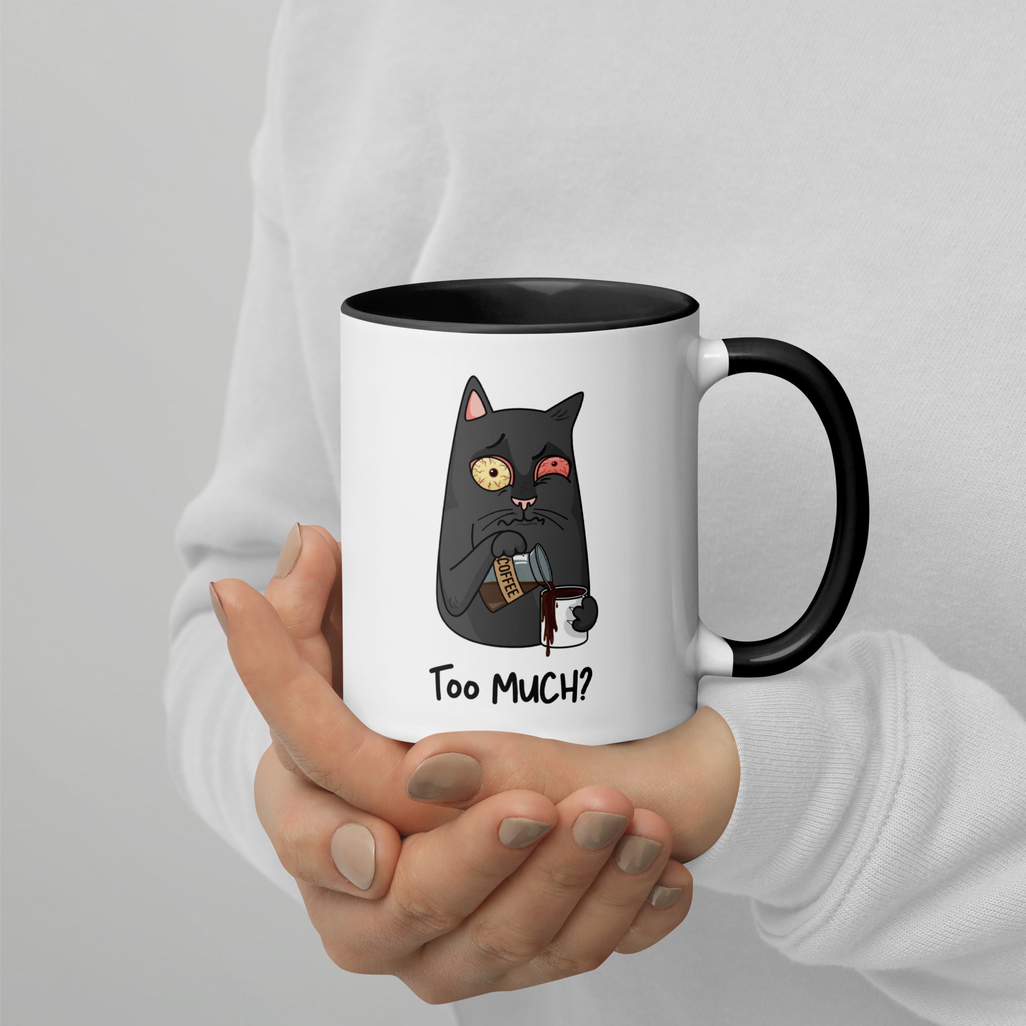 White "Too Much" Mug (showing interior and handle): Graphic of a wide-eyed/red-eyed gray cat pouring overflowing coffee into a cup, with coffee spilling down the side.