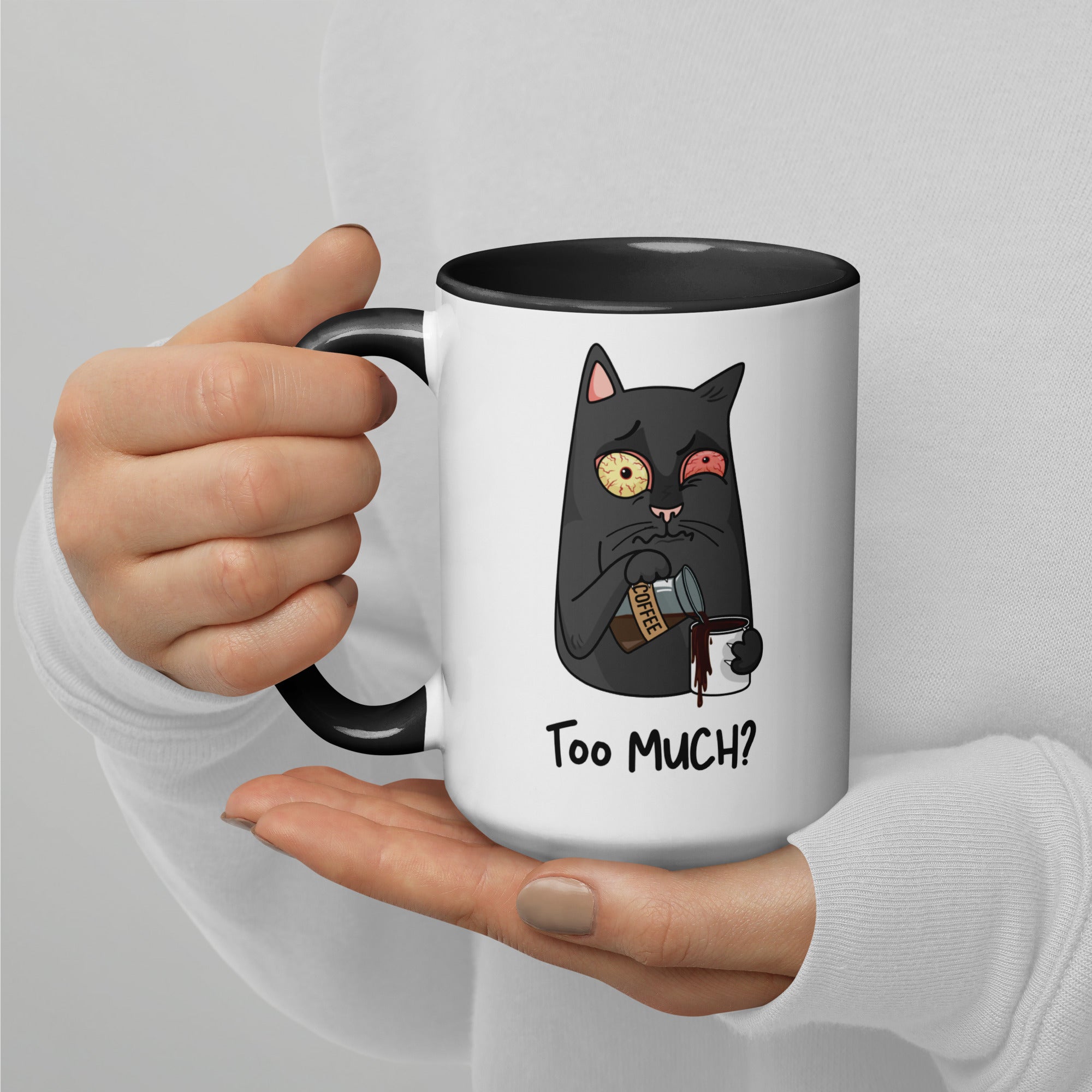 White "Too Much" Mug (showing interior and handle): Graphic of a wide-eyed/red-eyed gray cat pouring overflowing coffee into a cup, with coffee spilling down the side.