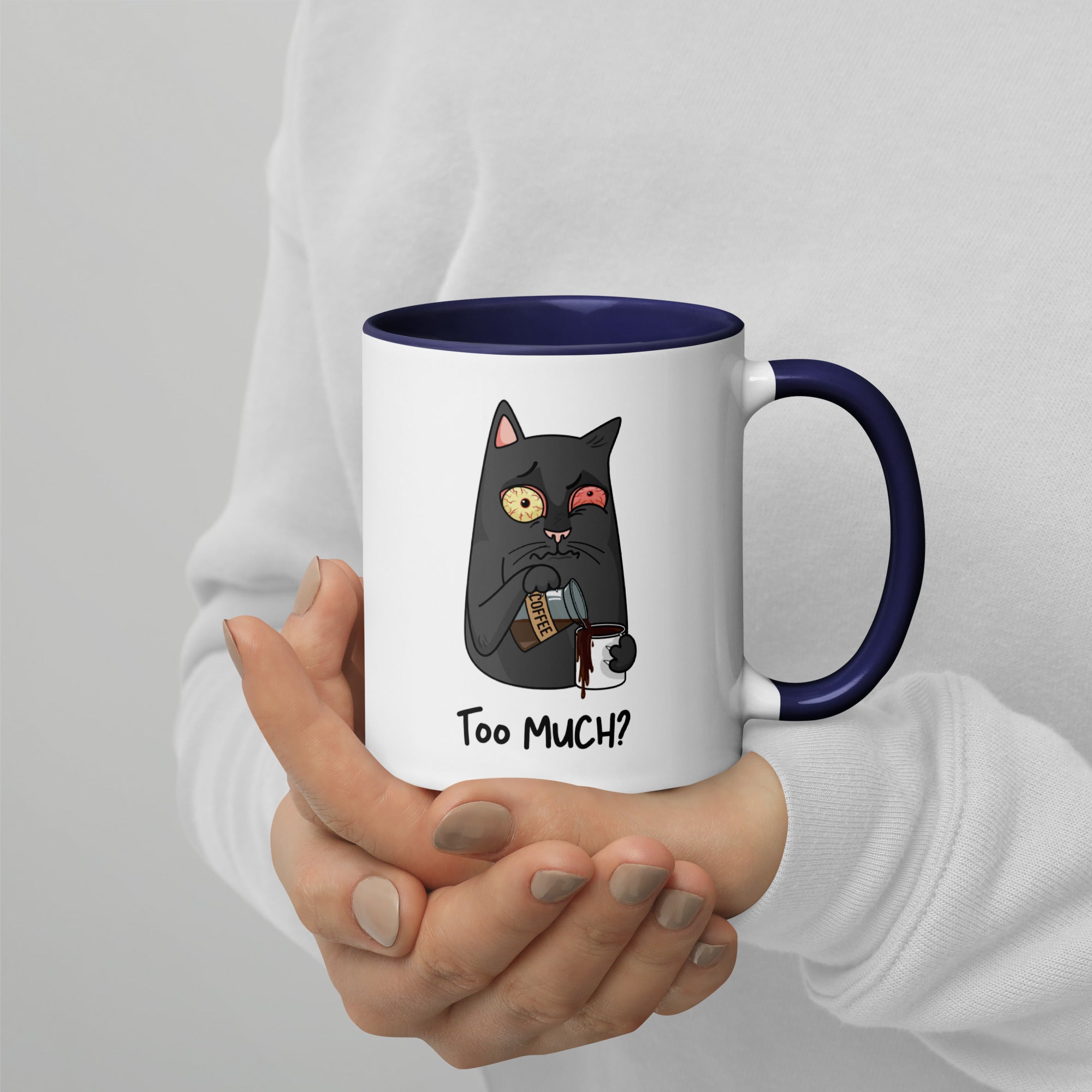 White "Too Much" Mug (showing interior and handle): Graphic of a wide-eyed/red-eyed gray cat pouring overflowing coffee into a cup, with coffee spilling down the side.