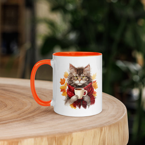 White "Autumn Kitty" Mug with an orange interior and rim. The graphic shows a cat wearing a plaid scarf and holding a steaming beverage, set against a backdrop of orange and yellow fall leaves.